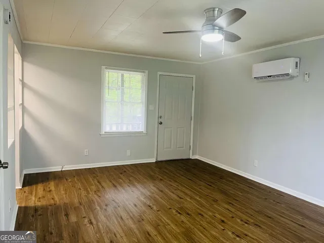 a view of an empty room with wooden floor and a window
