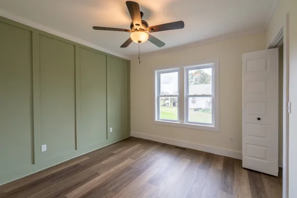 a view of an empty room with a window and wooden floor