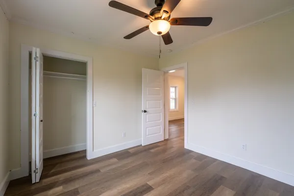 an empty room with wooden floor closet and ceiling fan