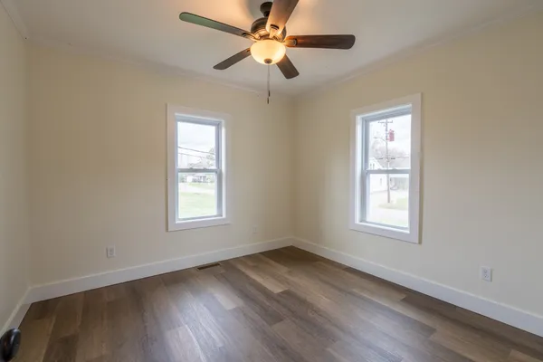 a view of an empty room with wooden floor and a window