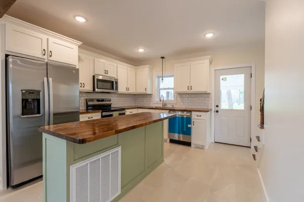 a kitchen with stainless steel appliances granite countertop a refrigerator a sink a stove a microwave and island