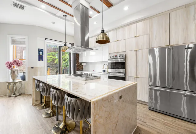 a kitchen with stainless steel appliances a kitchen island hardwood floor and a sink