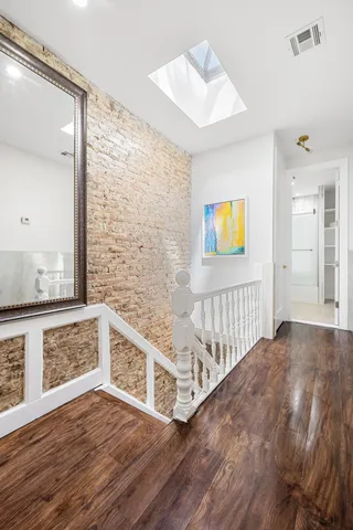 a view of an empty room and kitchen with wooden floor