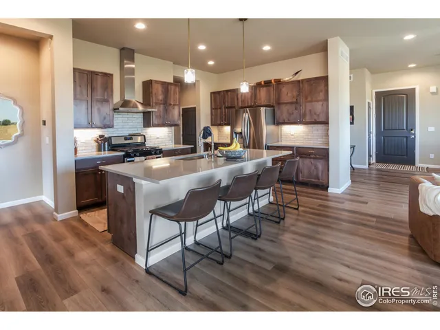 a kitchen with stainless steel appliances kitchen island granite countertop a table chairs and a refrigerator