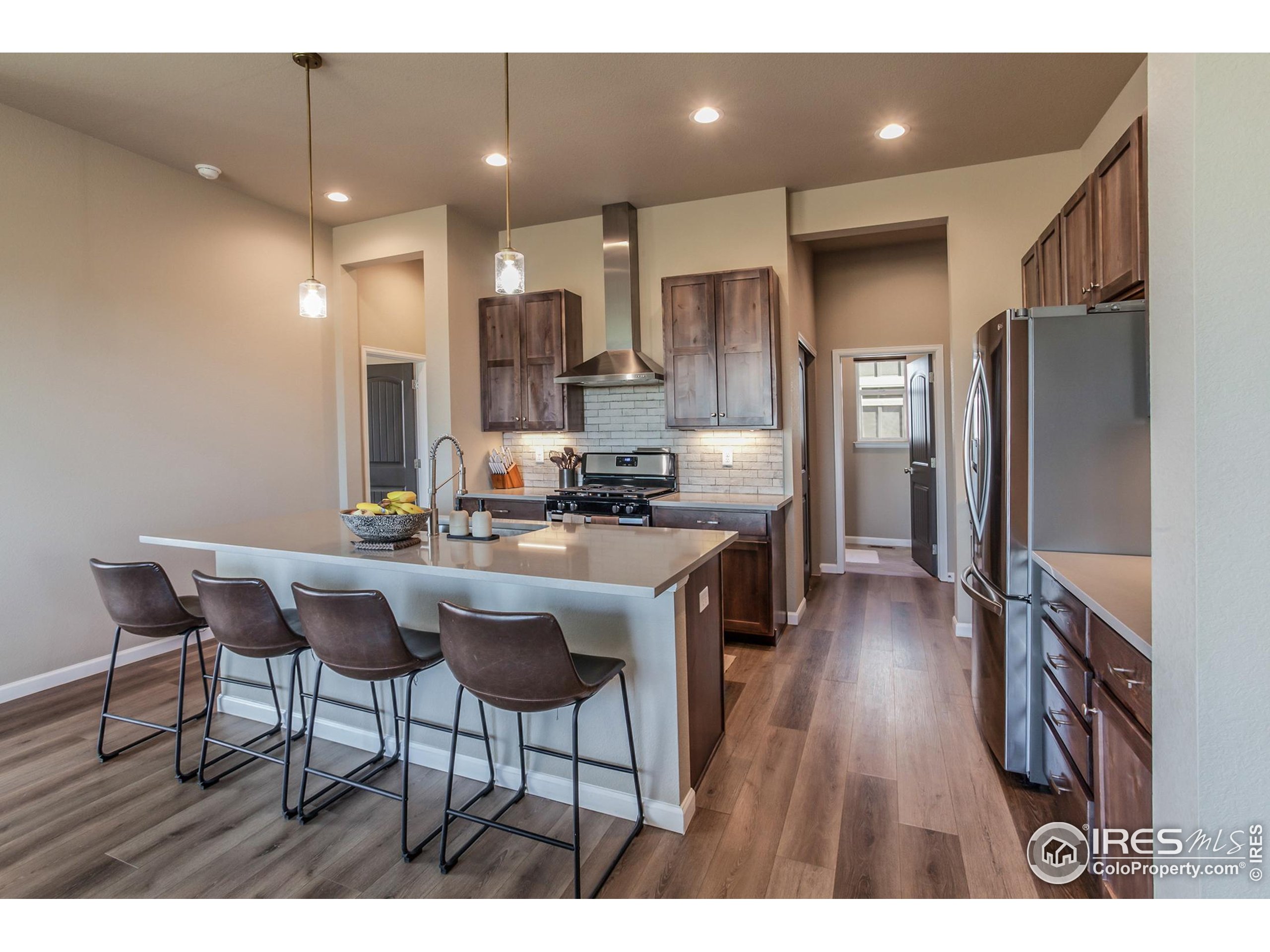 1231 105th Avenue Greeley, CO 80634 - Photo 18 of 43 a kitchen with stainless steel appliances kitchen island granite countertop a refrigerator a stove a sink dishwasher with a dining table and chairs