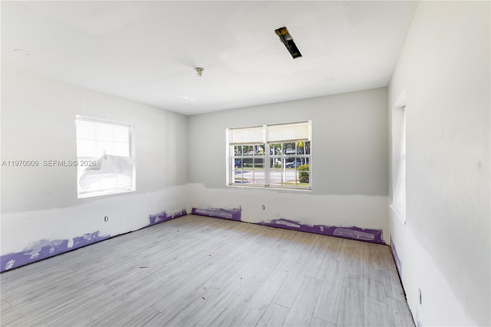 4555 Alton Road Miami Beach, FL 33140 - Photo 19 of 34 an empty room with wooden floor and windows
