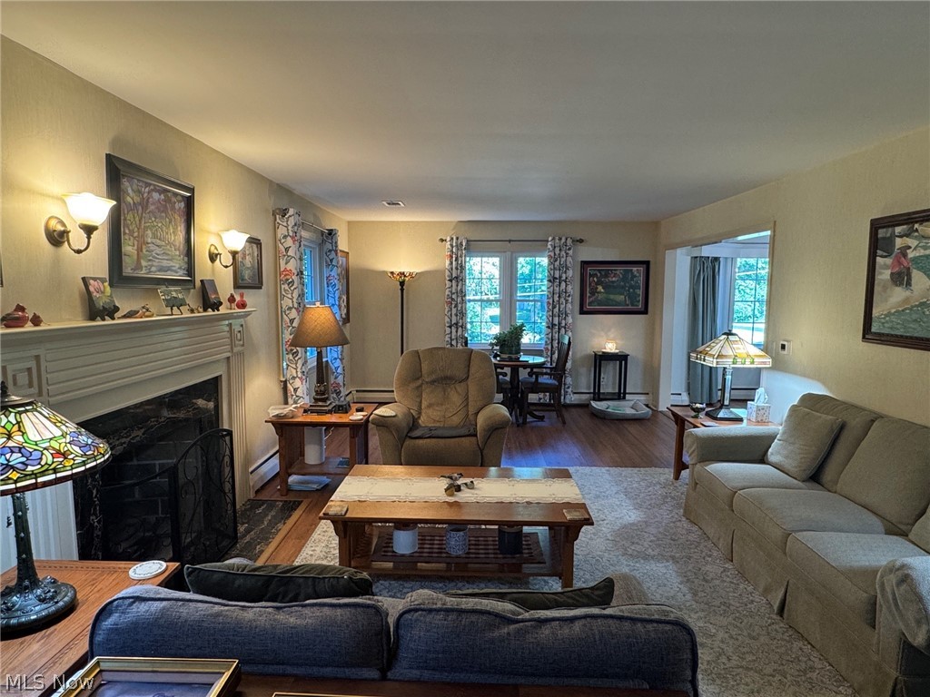Spacious living room featuring a wood-burning fireplace and multiple windows providing natural light and views of the outdoors