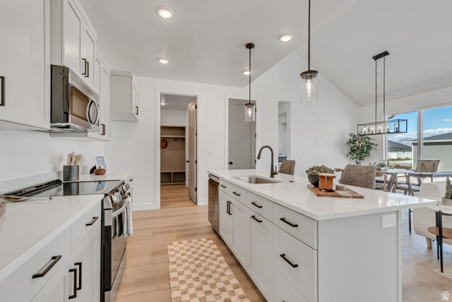 1302 1475 East, Unit 40 Payson, UT 84651 - Photo 7 of 34 Kitchen featuring stainless steel appliances, white cabinets, an island with sink, hanging light fixtures, and lofted ceiling