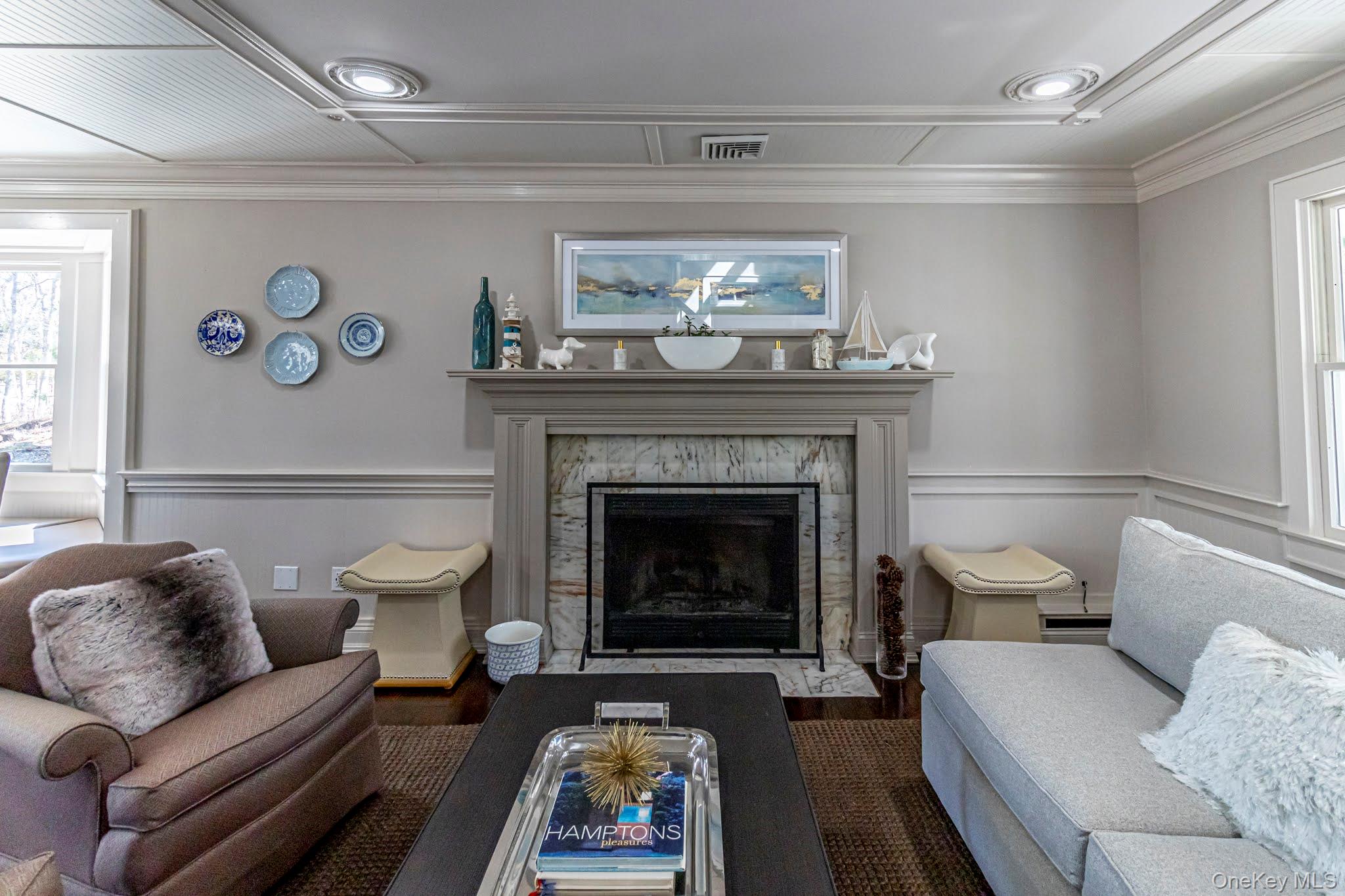 6 Bayview Terrace Hampton Bays, NY 11946 - Photo 3 of 36 Living area featuring wainscoting, crown molding, a fireplace, wood finished floors, and baseboard heating