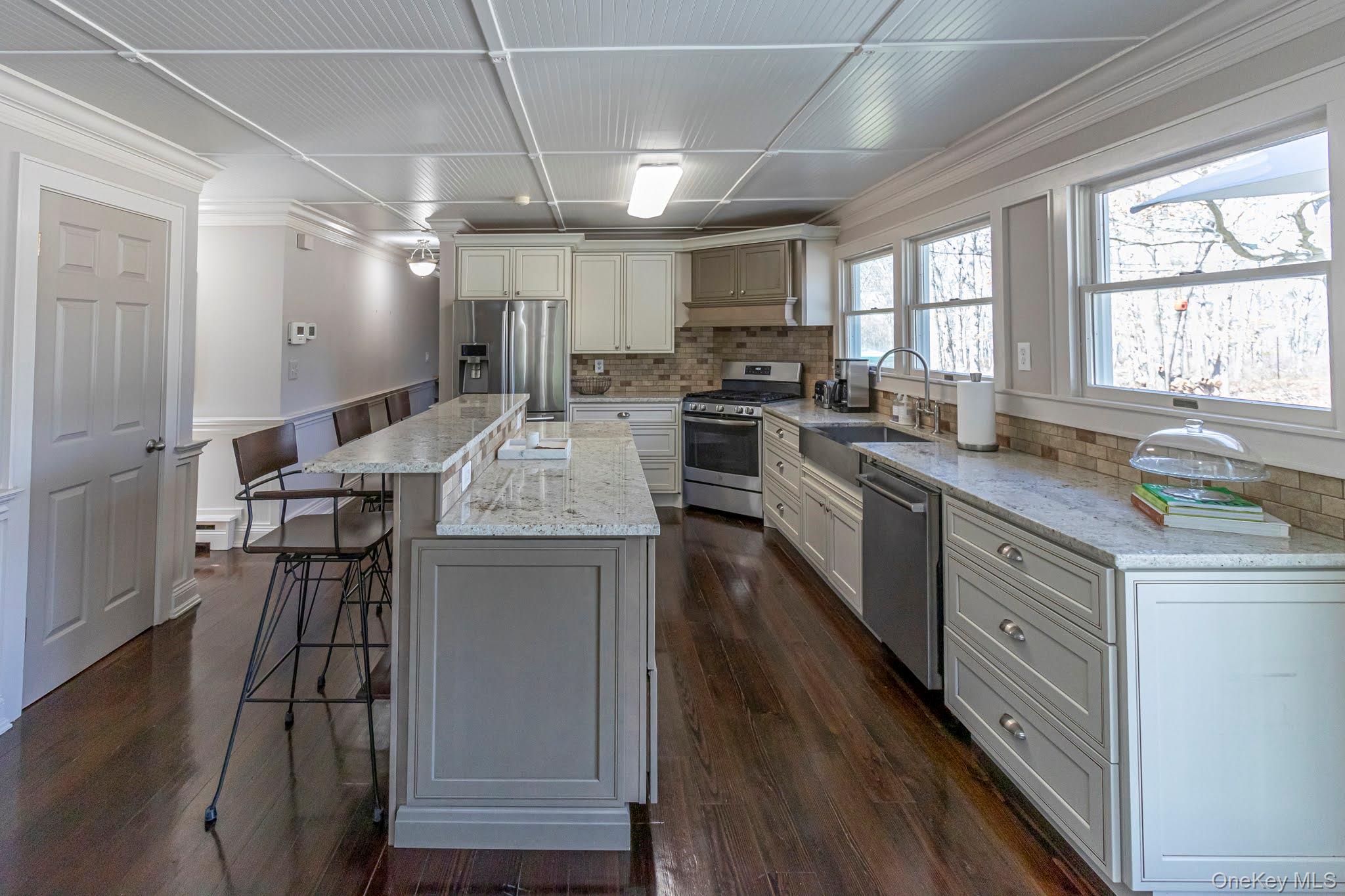 6 Bayview Terrace Hampton Bays, NY 11946 - Photo 7 of 36 Kitchen featuring a kitchen breakfast bar, a center island, appliances with stainless steel finishes, crown molding, and tasteful backsplash