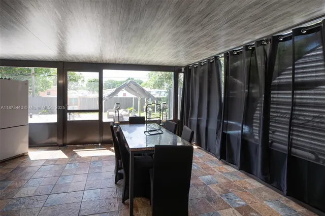 a living room with stainless steel appliances kitchen island granite countertop furniture a large window and a refrigerator