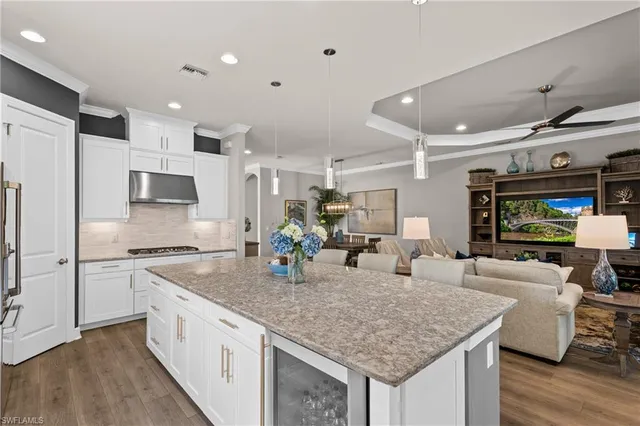 a kitchen with stainless steel appliances granite countertop a sink dishwasher a refrigerator and white cabinets with wooden floor