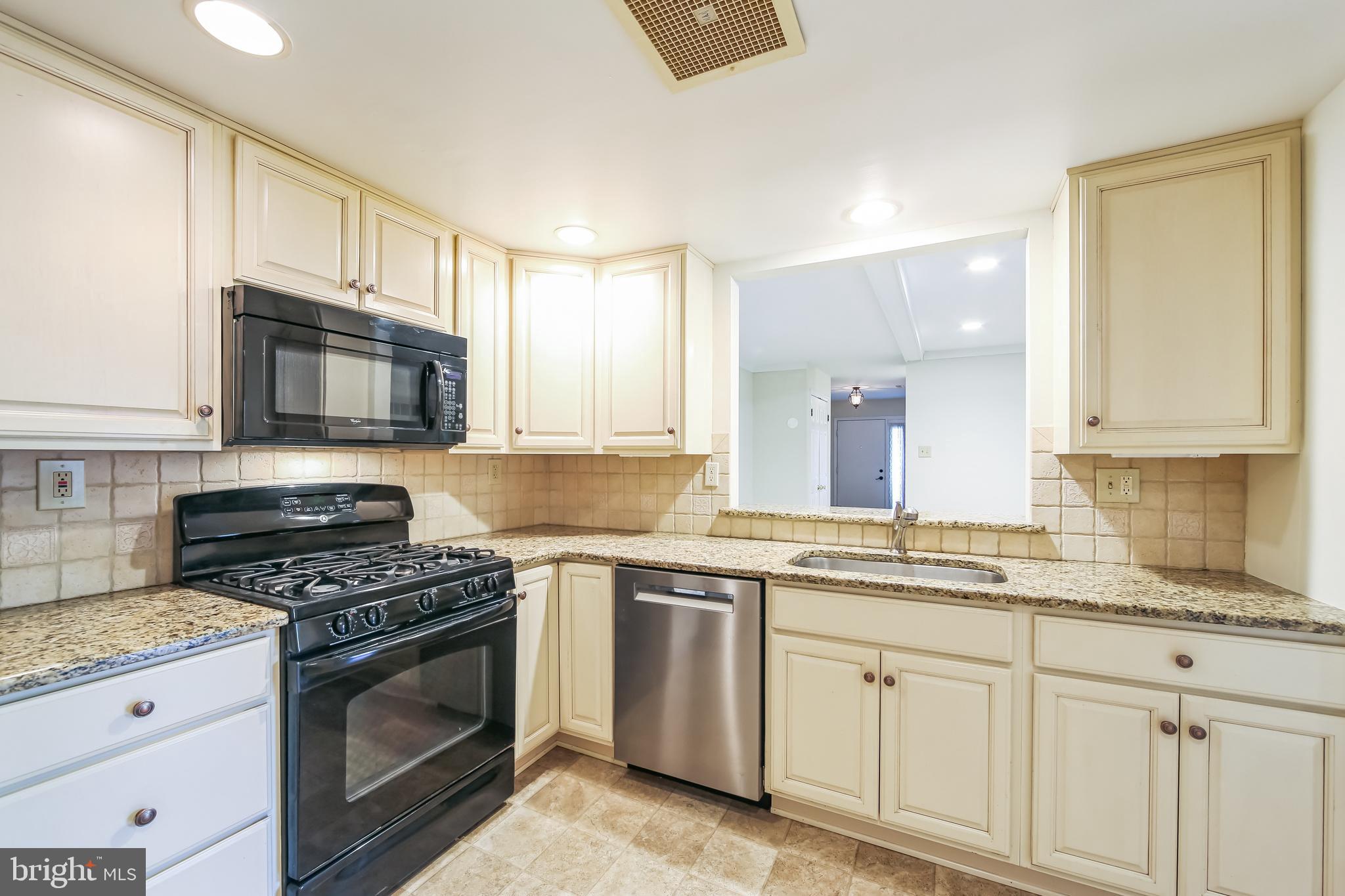 1804 Mountainview Drive, Unit 1804 Chesterbrook, PA 19087 - Photo 10 of 20 a kitchen with granite countertop a stove a sink and wooden cabinets