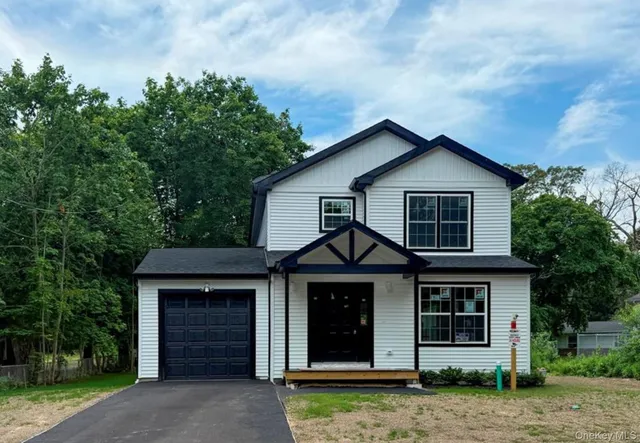 a view of a house with a yard and large tree