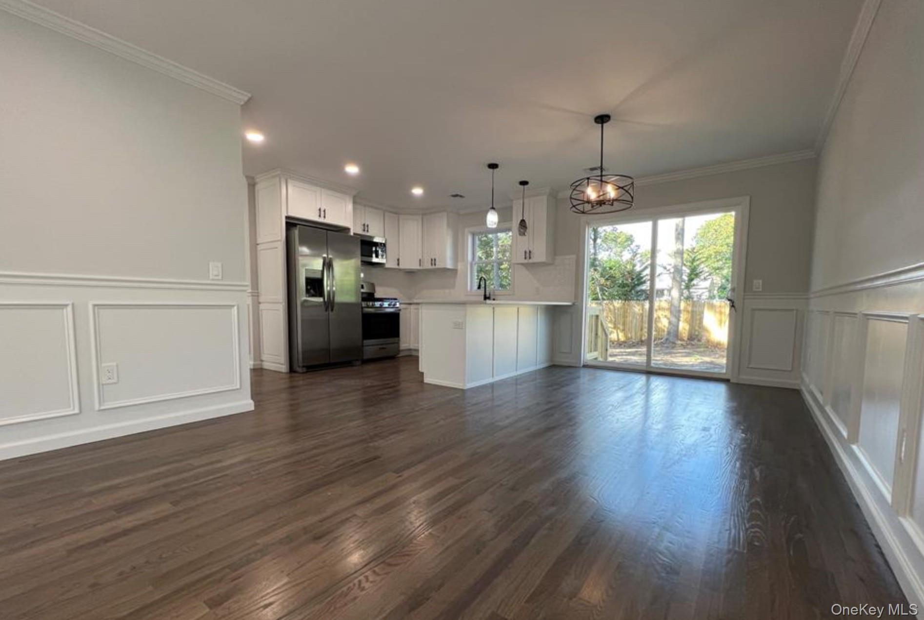 492 Blue Point Road Farmingville, NY 11738 - Photo 2 of 9 a view of an empty room and kitchen with wooden floor