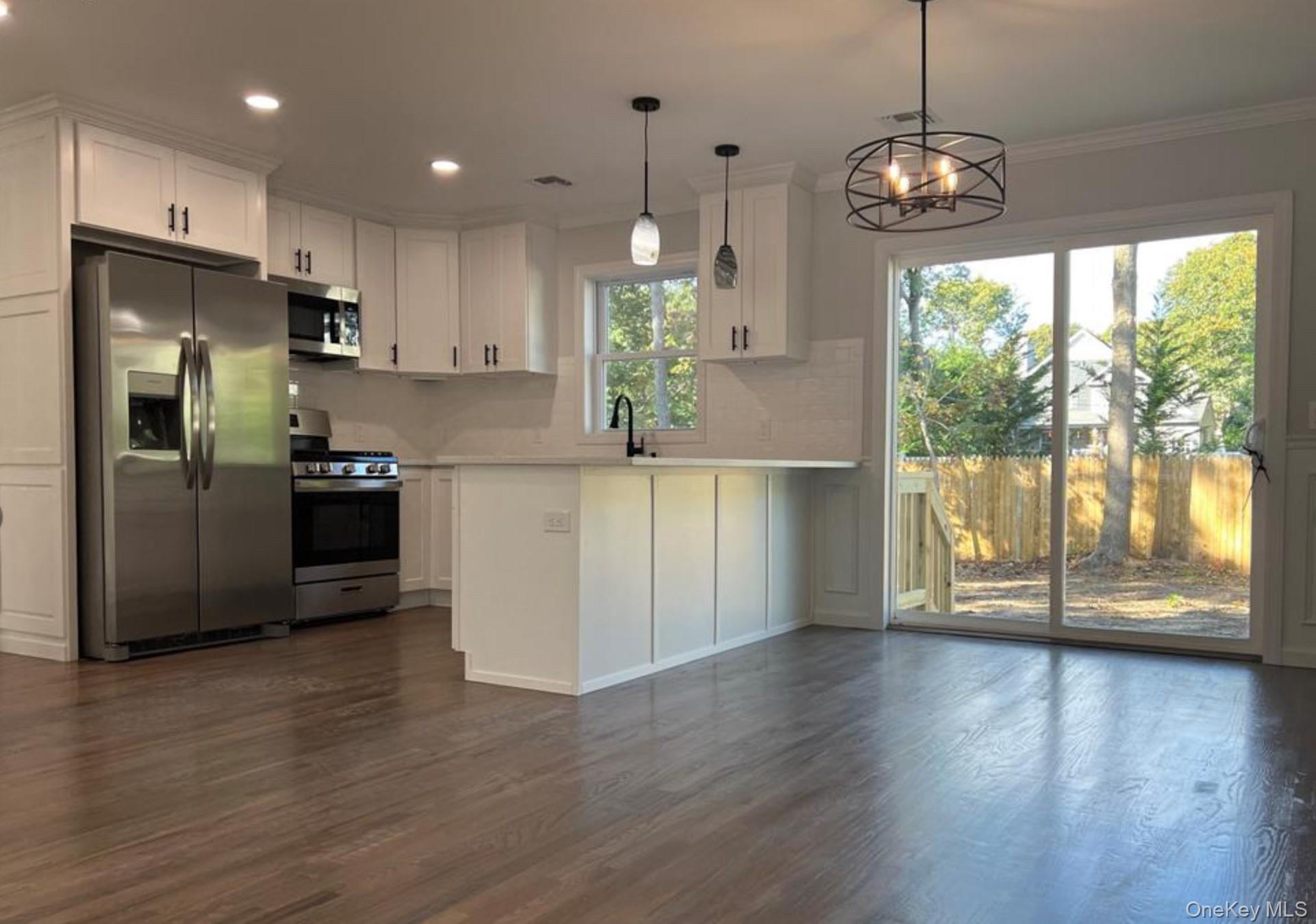 492 Blue Point Road Farmingville, NY 11738 - Photo 3 of 9 a view of a kitchen with wooden floor and stainless steel appliances