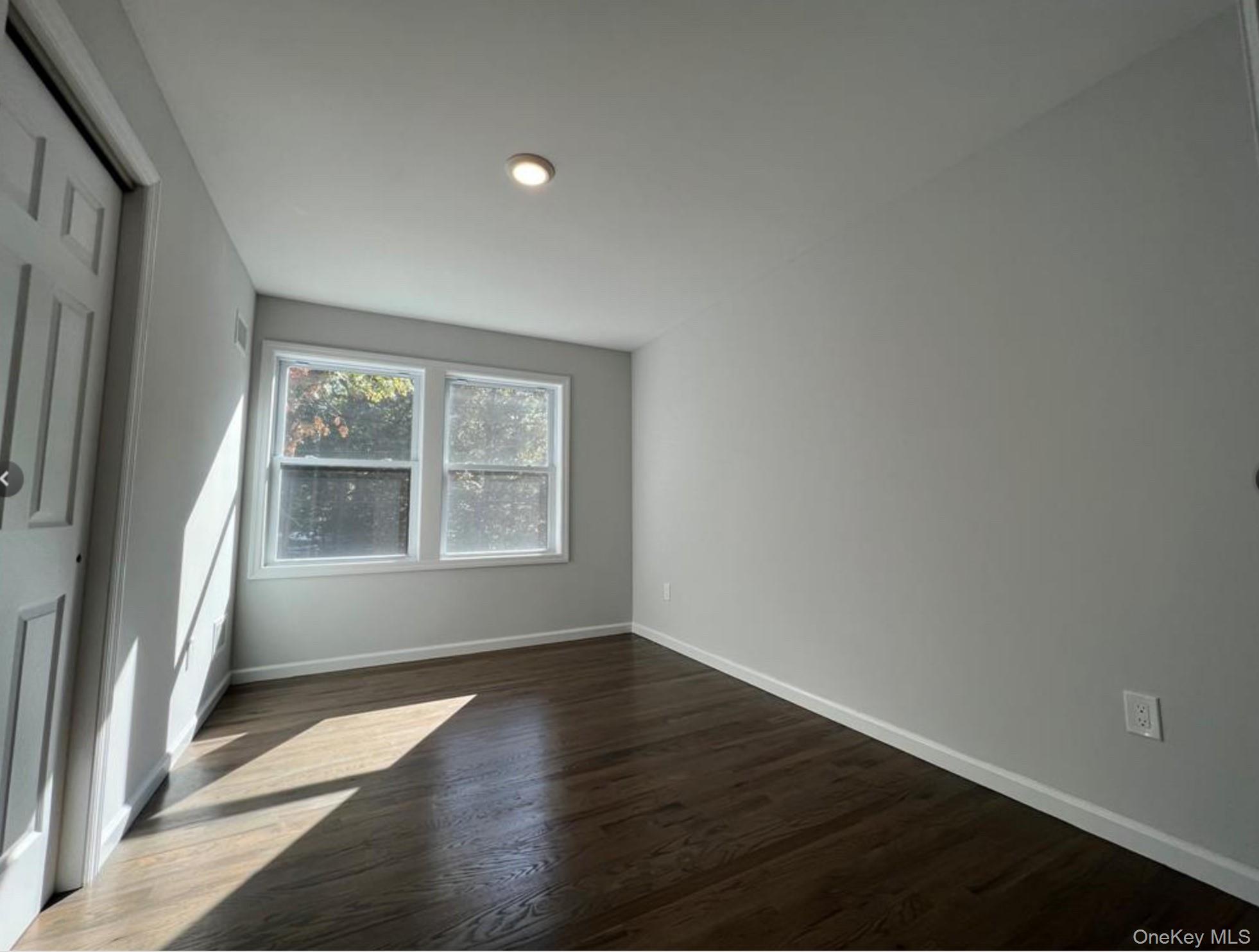 492 Blue Point Road Farmingville, NY 11738 - Photo 7 of 9 an empty room with wooden floor and windows