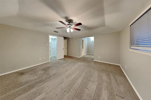 a view of an empty room with a chandelier fan
