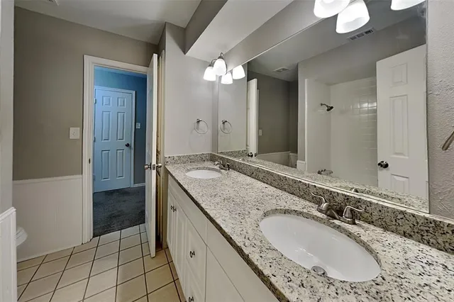 a bathroom with a granite countertop sink a mirror and a bathtub