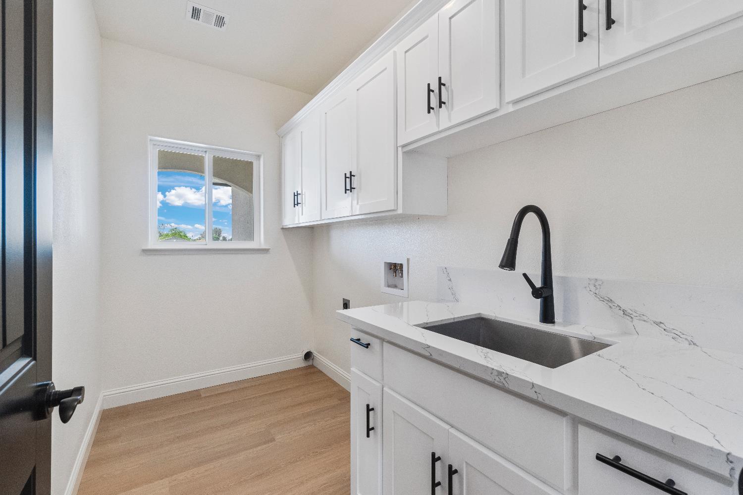 21035 Forest Glen Road Madera, CA 93638 - Photo 18 of 31 a kitchen with stainless steel appliances granite countertop a sink a stove and white cabinets with wooden floor