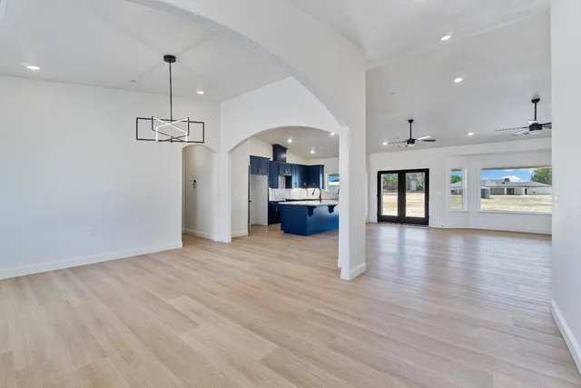 an empty room with wooden floor ceiling fan and windows
