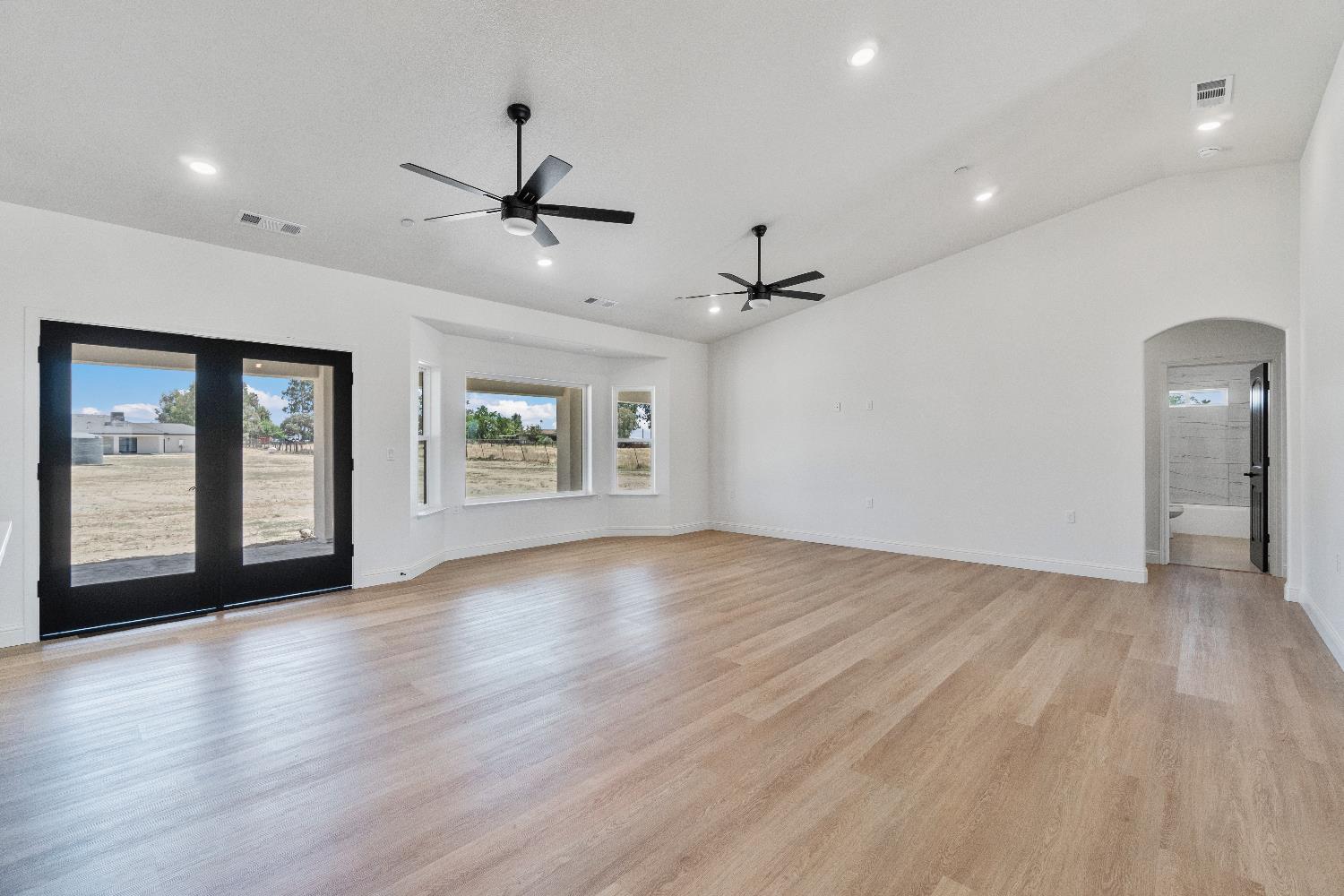 21035 Forest Glen Road Madera, CA 93638 - Photo 7 of 31 an empty room with wooden floor ceiling fan and windows