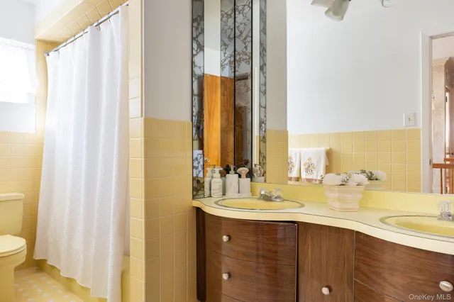 a bathroom with a double vanity sink toilet and a tub