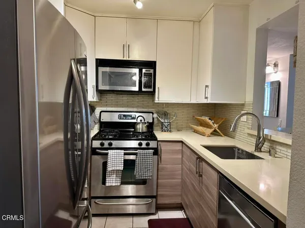 a kitchen with stainless steel appliances granite countertop a refrigerator a stove and a sink with wooden floor