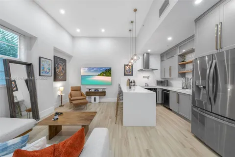 a kitchen with stainless steel appliances a refrigerator a stove a sink dishwasher and white cabinets with wooden floor