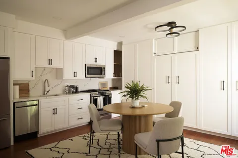 a kitchen with stainless steel appliances a white table and chairs in it