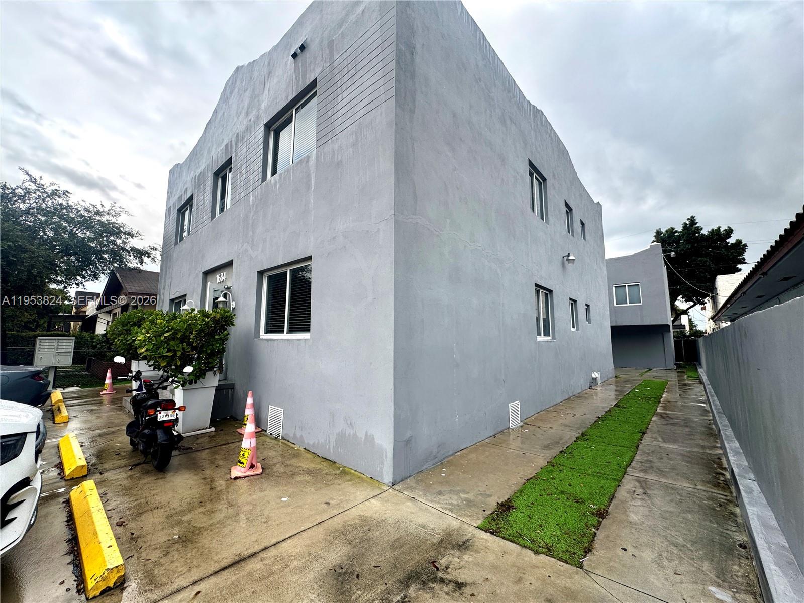 1684 Southwest 10th Street Miami, FL 33135 - Photo 2 of 14 a view of a white house with many windows next to a yard