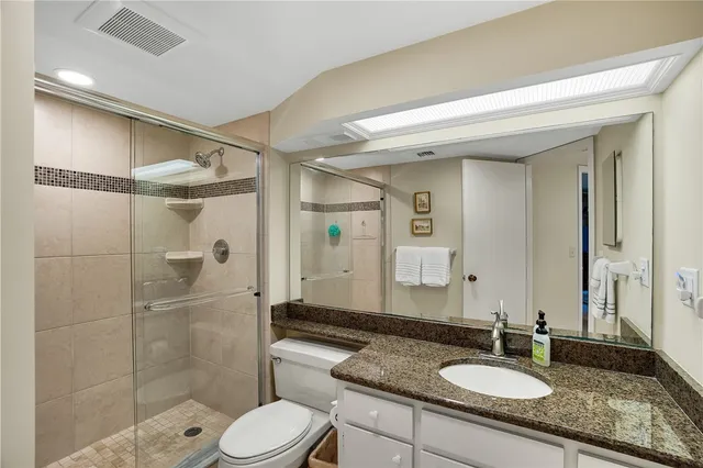 a bathroom with a shower sink vanity mirror and toilet