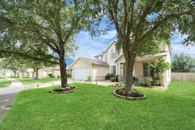 a front view of a house with garden and trees