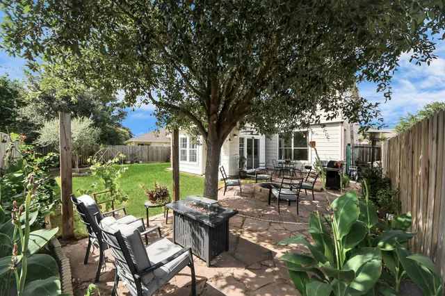 a view of a patio with table and chairs potted plants and large tree