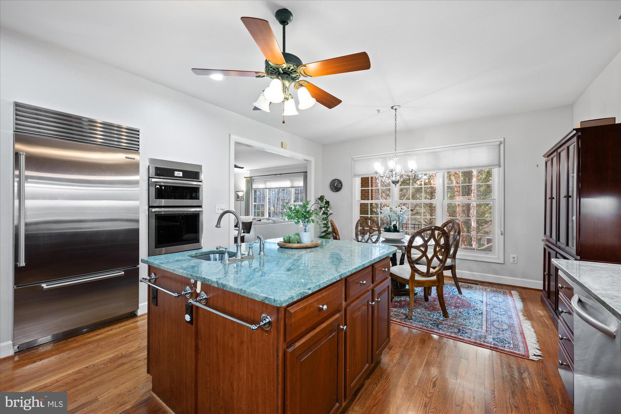 7822 Hidden Meadow Terrace Potomac, MD 20854 - Photo 12 of 29 a kitchen with stainless steel appliances kitchen island granite countertop a refrigerator a stove a sink a dining table and chairs with wooden floor