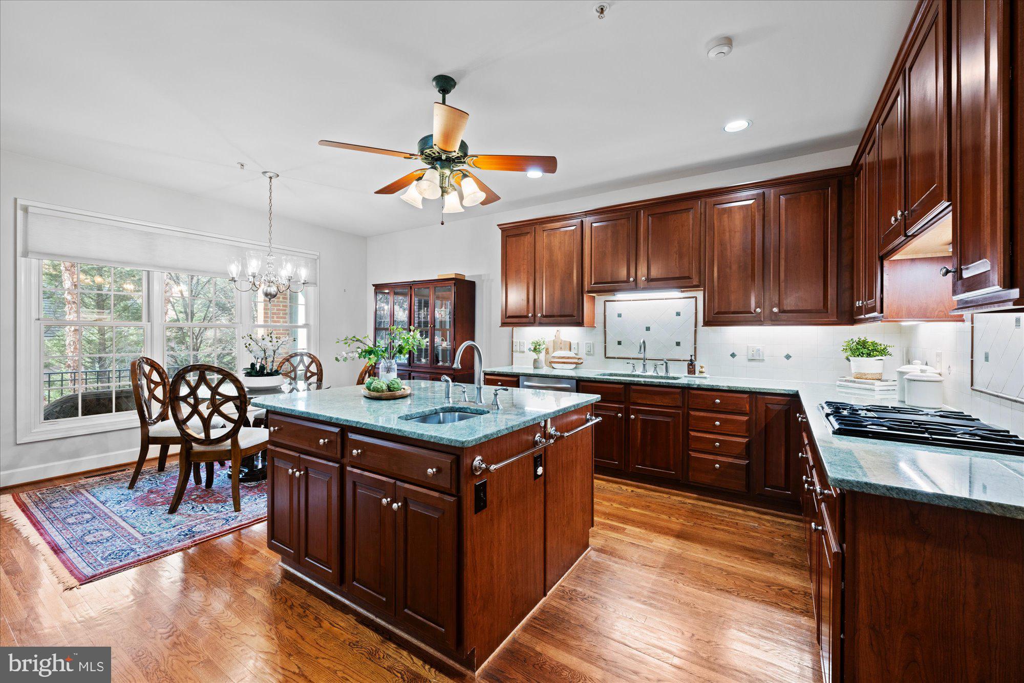 7822 Hidden Meadow Terrace Potomac, MD 20854 - Photo 10 of 29 a kitchen with stainless steel appliances granite countertop a stove a refrigerator a sink a dining table and chairs with wooden floor