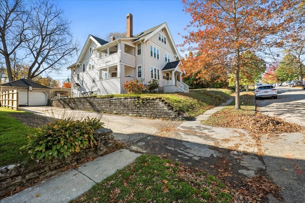 a view of a white house next to a road with a yard