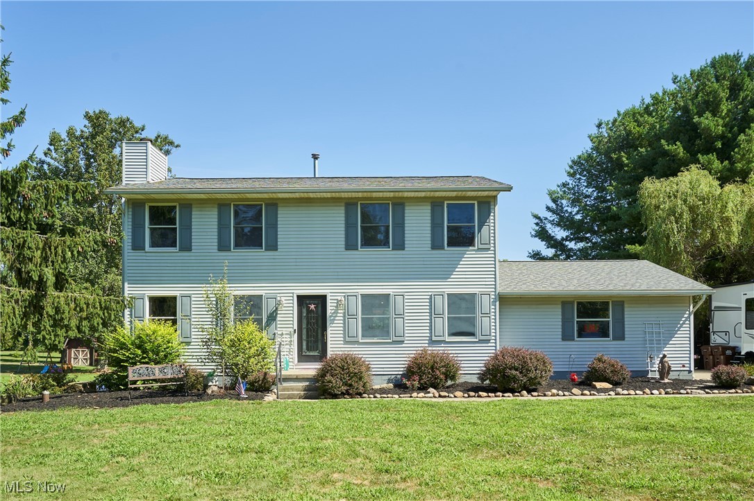 Colonial inspired home featuring a front lawn and a chimney