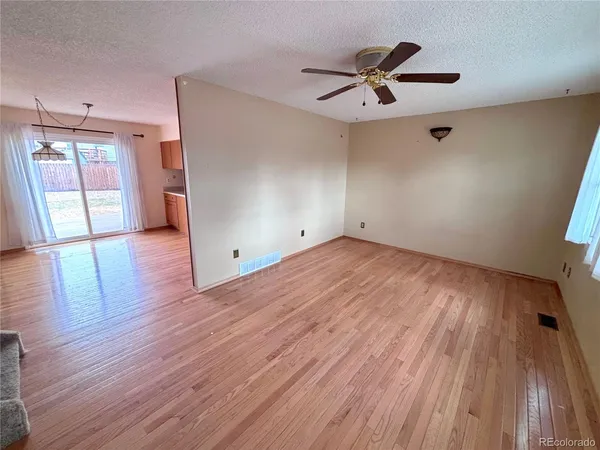 a view of empty room with wooden floor and fan