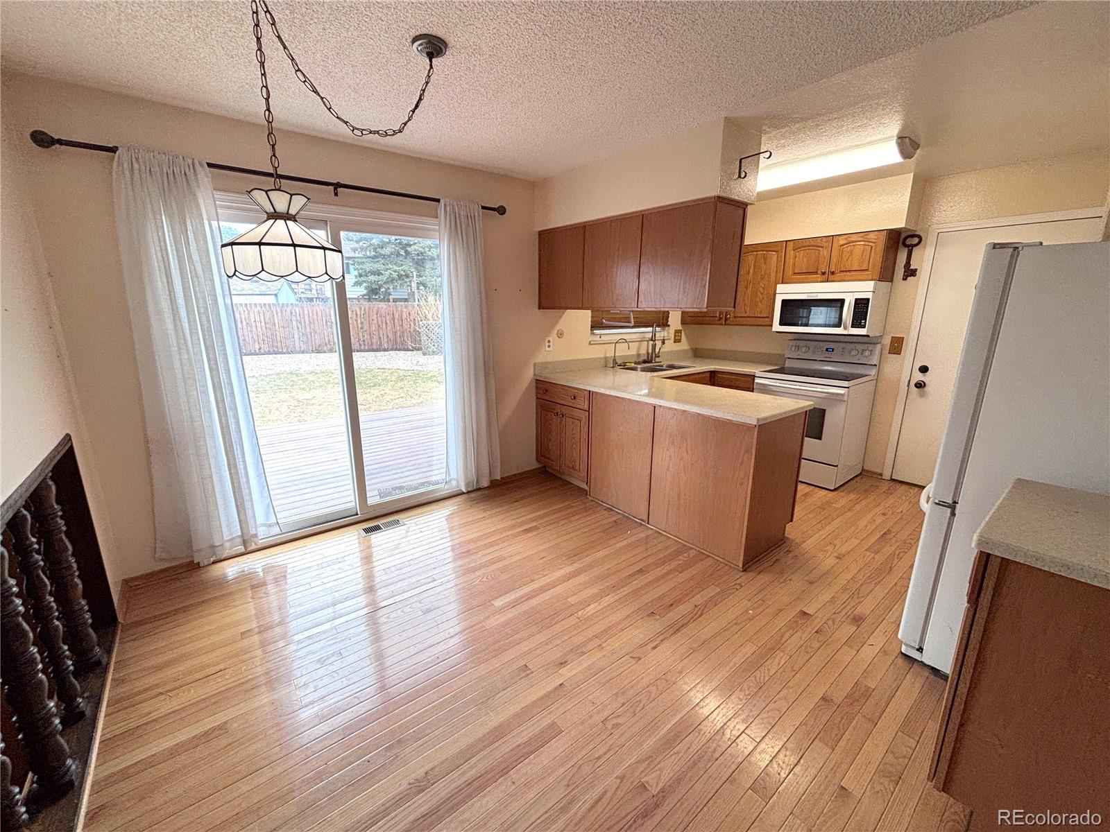6910 Roaring Spring Terrace Fountain, CO 80817 - Photo 3 of 14 a kitchen with stainless steel appliances granite countertop a refrigerator a sink dishwasher a stove a refrigerator with wooden floor