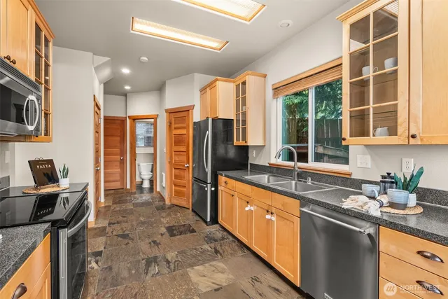 a kitchen with stainless steel appliances granite countertop sink stove and refrigerator
