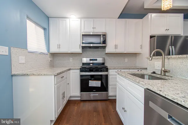 a view of kitchen with stainless steel appliances a refrigerator and wooden floor