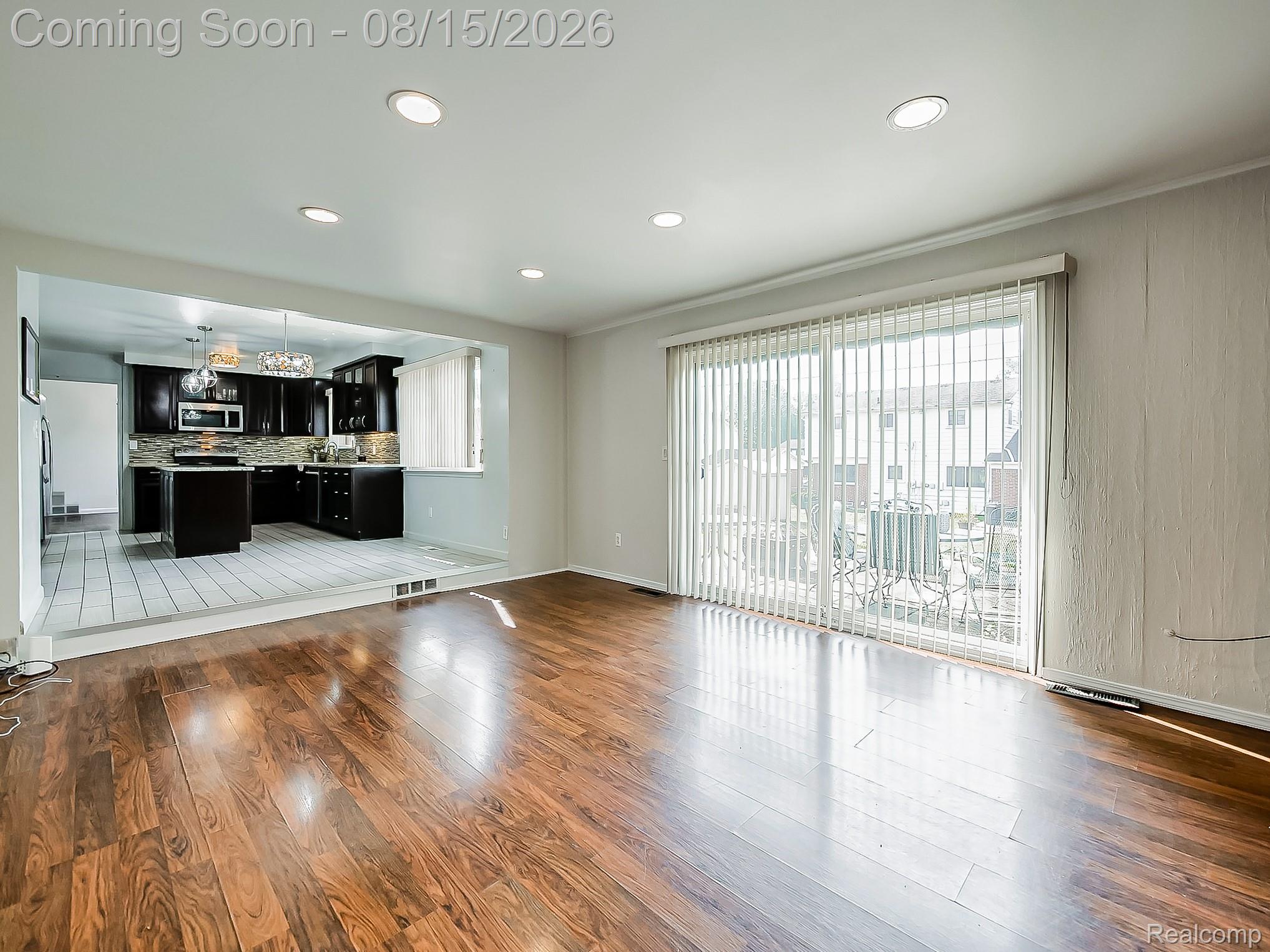21131 Harvard Road Southfield, MI 48076 - Photo 7 of 33 Spacious open-concept living area featuring rich wood-finish flooring throughout, recessed ceiling lighting, and abundant natural light from expansive sliding glass doors with vertical blinds