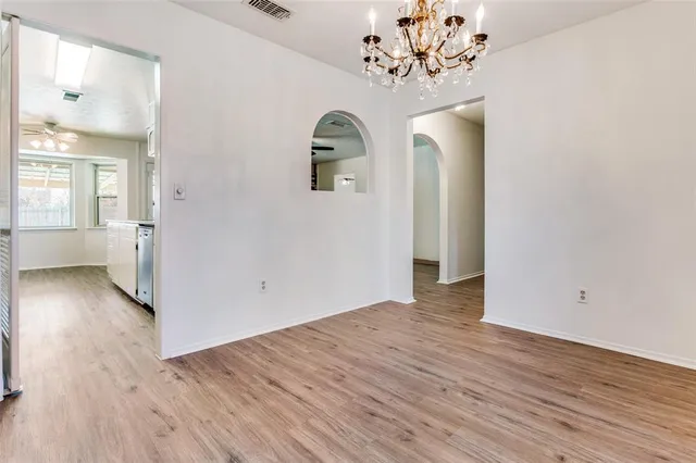 an empty room with wooden floor closet and windows