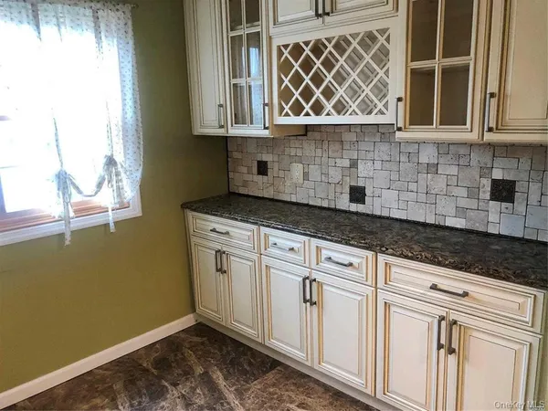a kitchen with granite countertop white cabinets and a window
