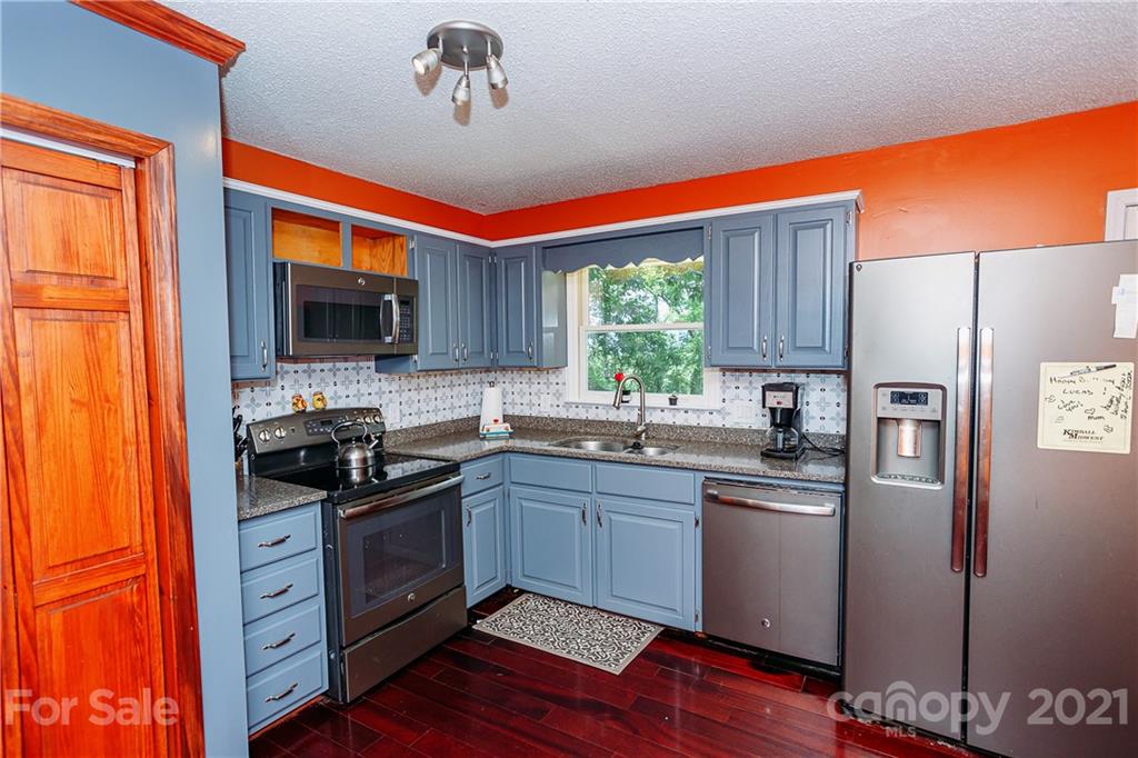 507 Vision Road Canton, NC 28716 - Photo 12 of 39 a kitchen with stainless steel appliances granite countertop a stove top oven a sink dishwasher and a refrigerator with wooden floor