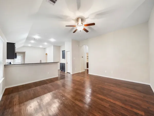 a view of an empty room with window and wooden floor