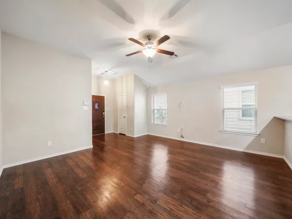 a view of an empty room with wooden floor and a window