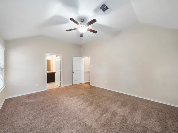 an empty room with chandelier fan and windows