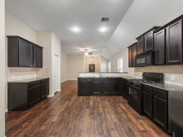 a large kitchen with stainless steel appliances granite countertop a stove a sink dishwasher and a refrigerator with wooden floor